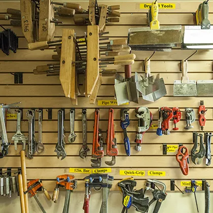Wall of local tool library with a large assortment of application tools hanging from a hardboard panel